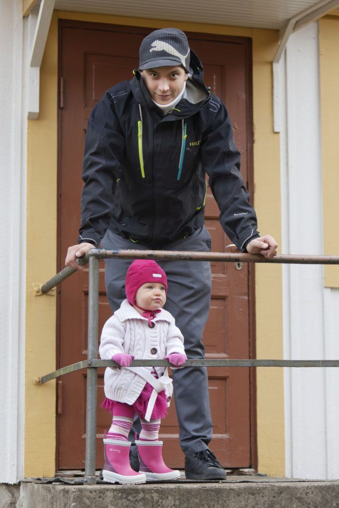 Turvallinen isä ja pieni tyttö portailla katsomassa eri suuntiin. Kuvan isä ei ole Jussi-työn asiakas. 